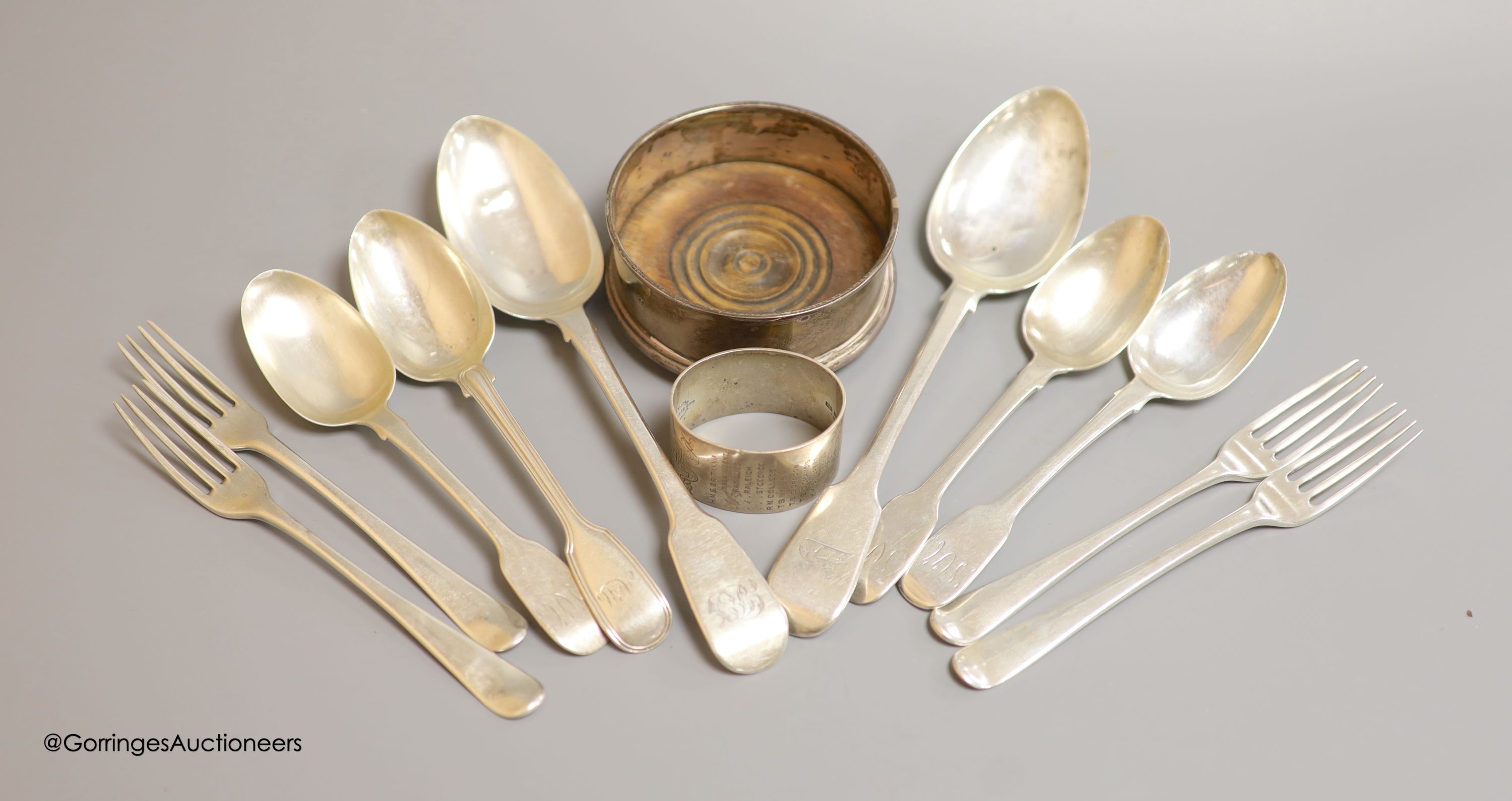 Four George III silver forks, six spoons, a later bottle coaster and a napkin ring